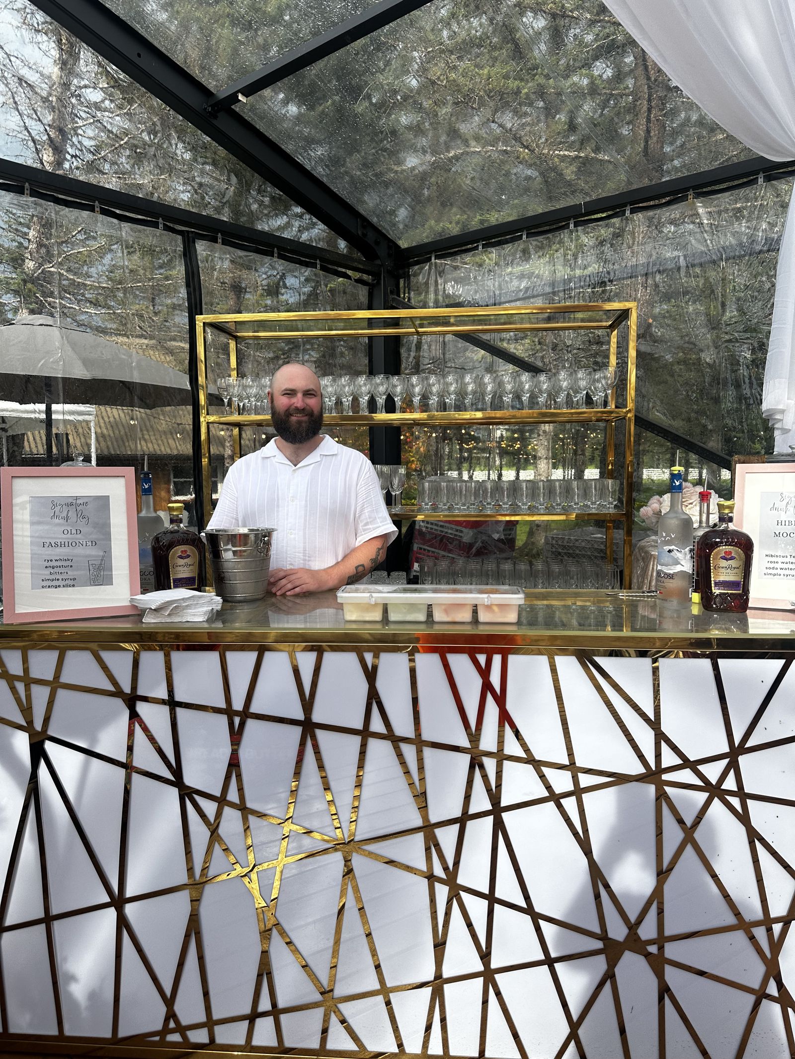 Bartenders pouring drinks at the Bubbles and Brews stationary bar setup inside a glass event tent