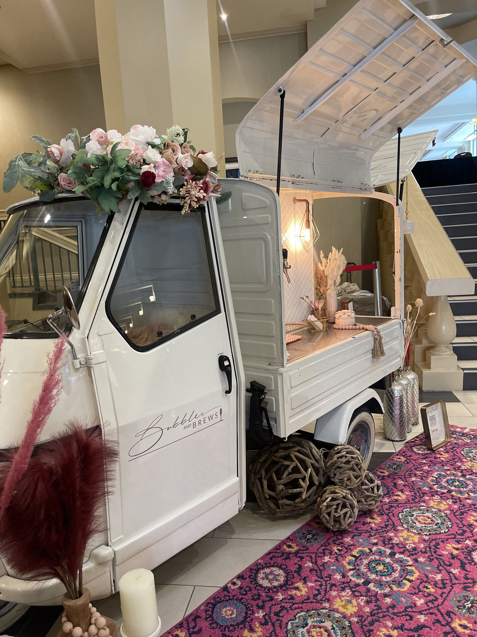 Bubbles and Brews mobile bar set up indoors in a hotel lobby with a marble staircase