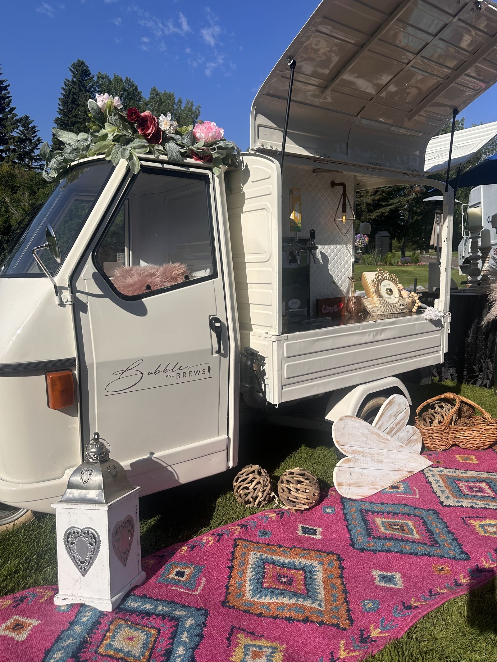 Boho-styled Bubbles and Brews mobile bar setup with a Moroccan rug and dried florals