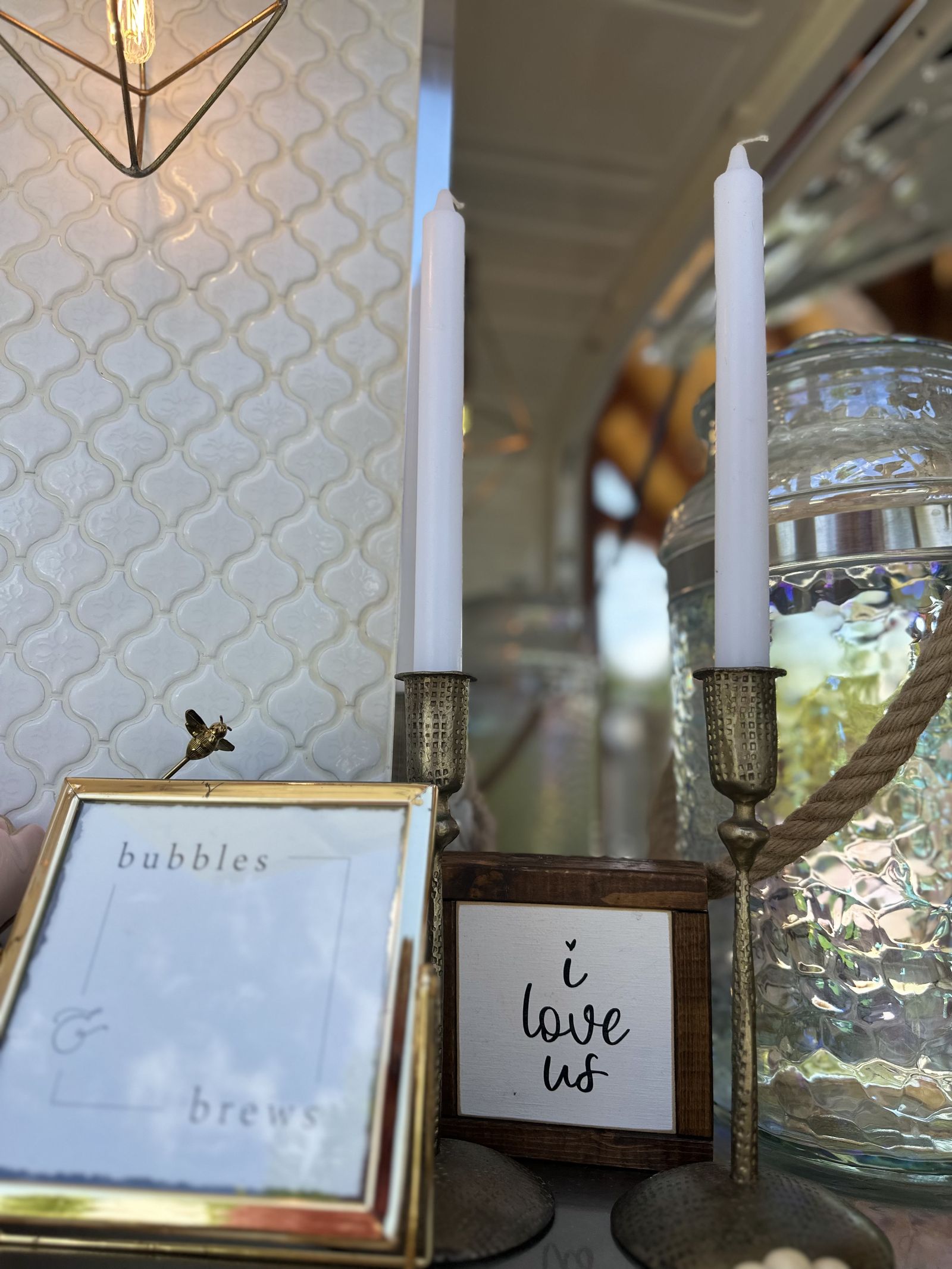 Wedding detail shot of a framed 'I love us' sign beside candles on the Bubbles and Brews mobile bar