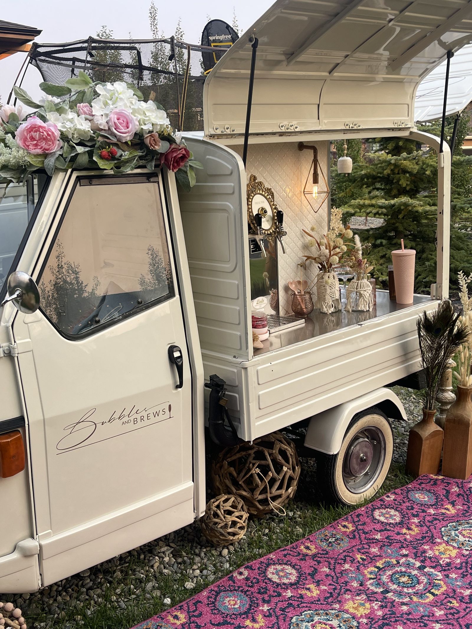 Mobile bar styled with peacock feathers and dried florals at dusk