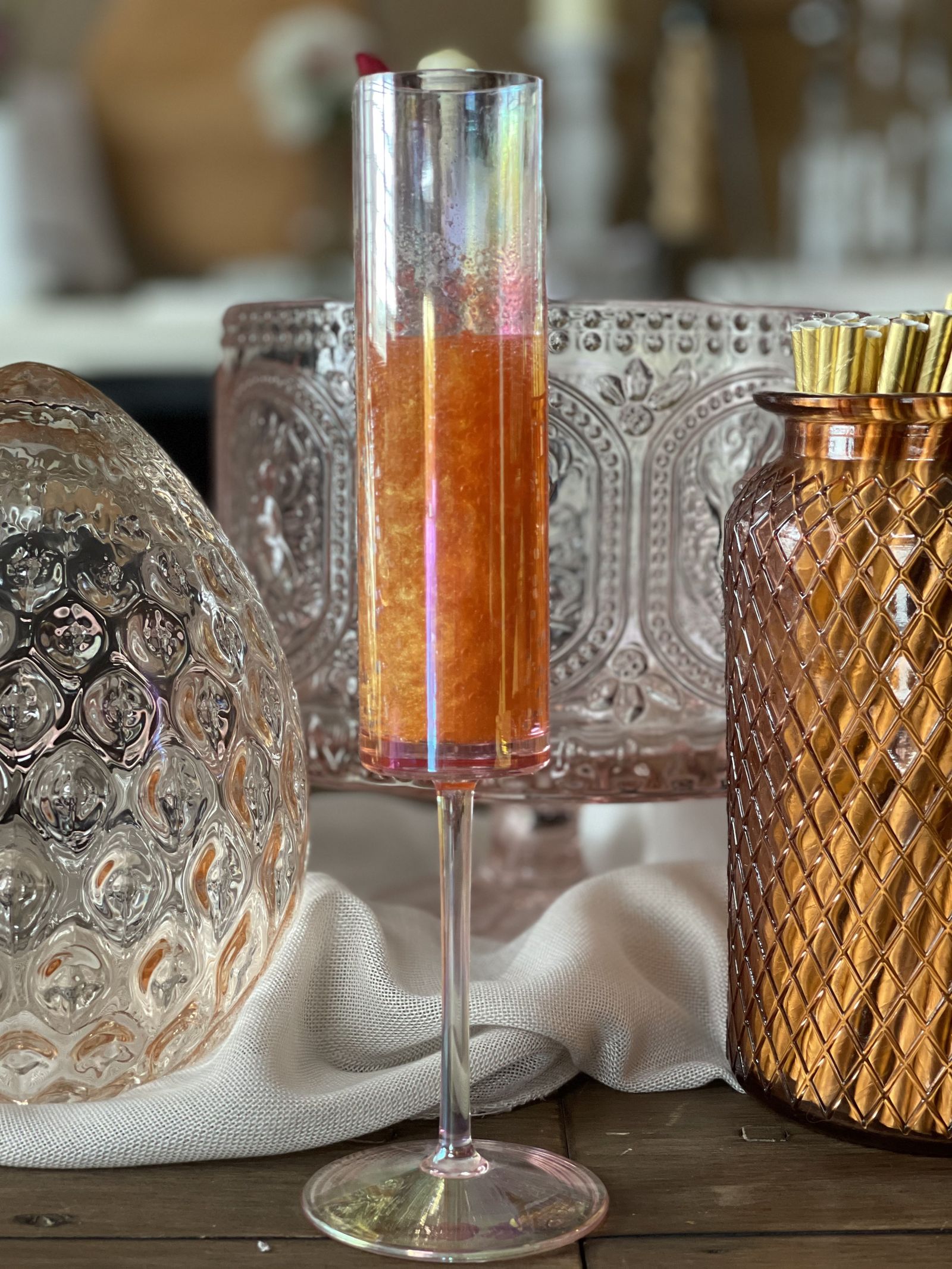 Styled sparkling prosecco cocktail in an iridescent flute with gold straws