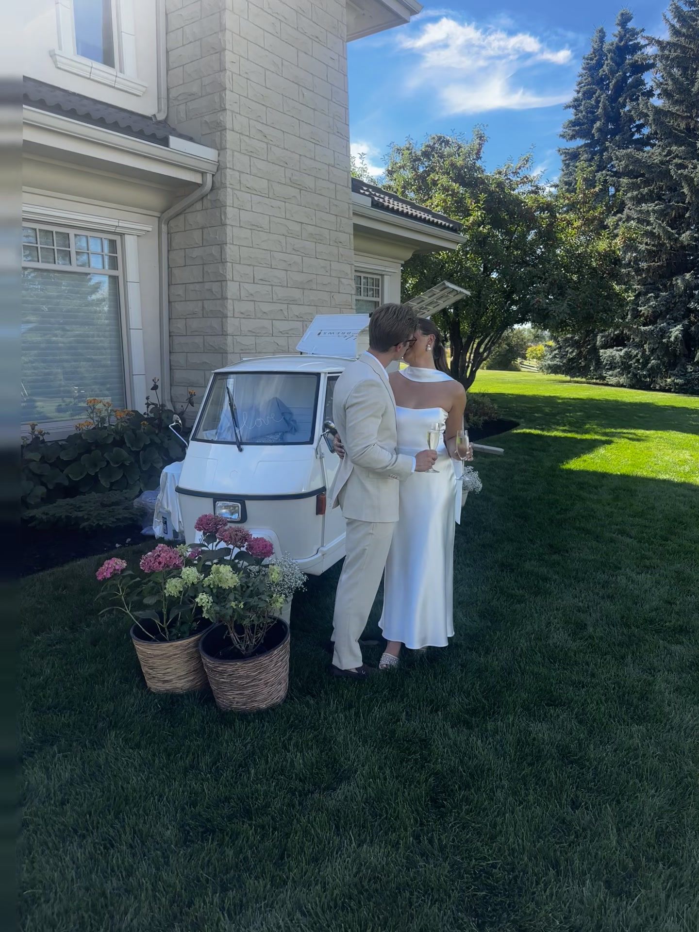Engaged couple sharing a champagne toast in front of the mobile bar in a Calgary backyard setting