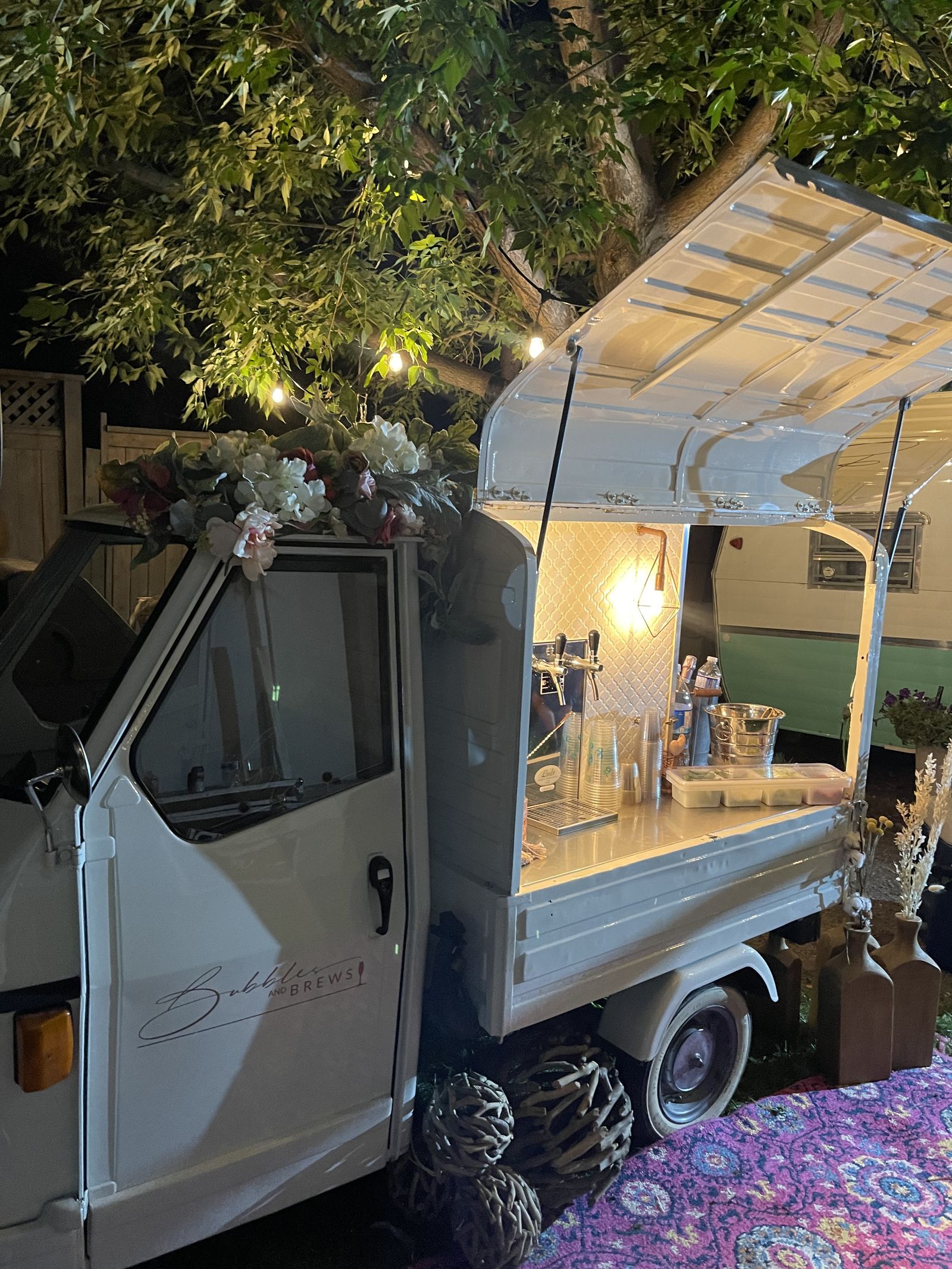 Mobile bar lit up at night under string lights in a backyard setting