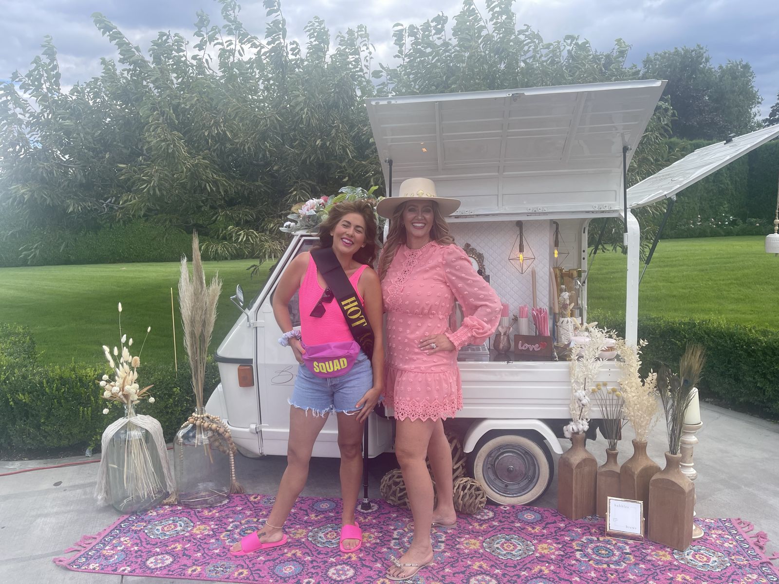 Bachelorette party guests wearing a 'Hot Squad' sash in front of the Bubbles and Brews truck