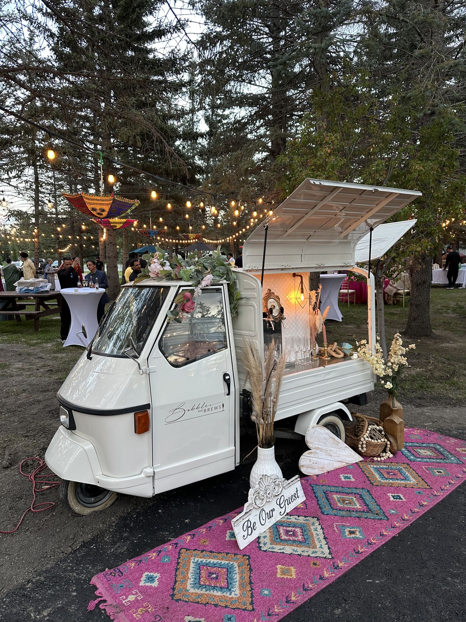 Bubbles and Brews mobile bar at an evening park event in Calgary with string lights and picnic tables