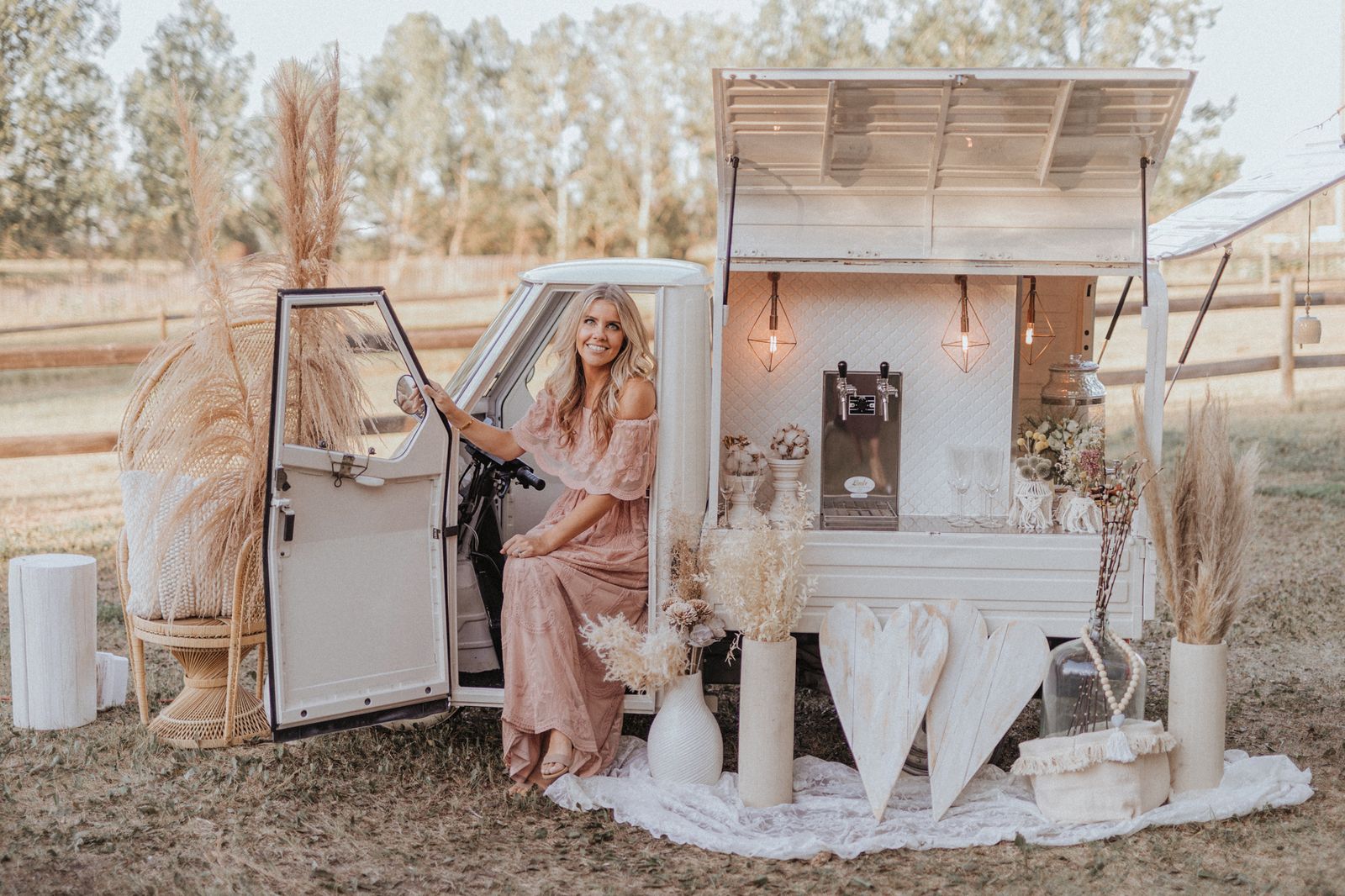 Professional photography of a boho-styled Bubbles and Brews mobile bar with a wicker peacock chair and pampas grass