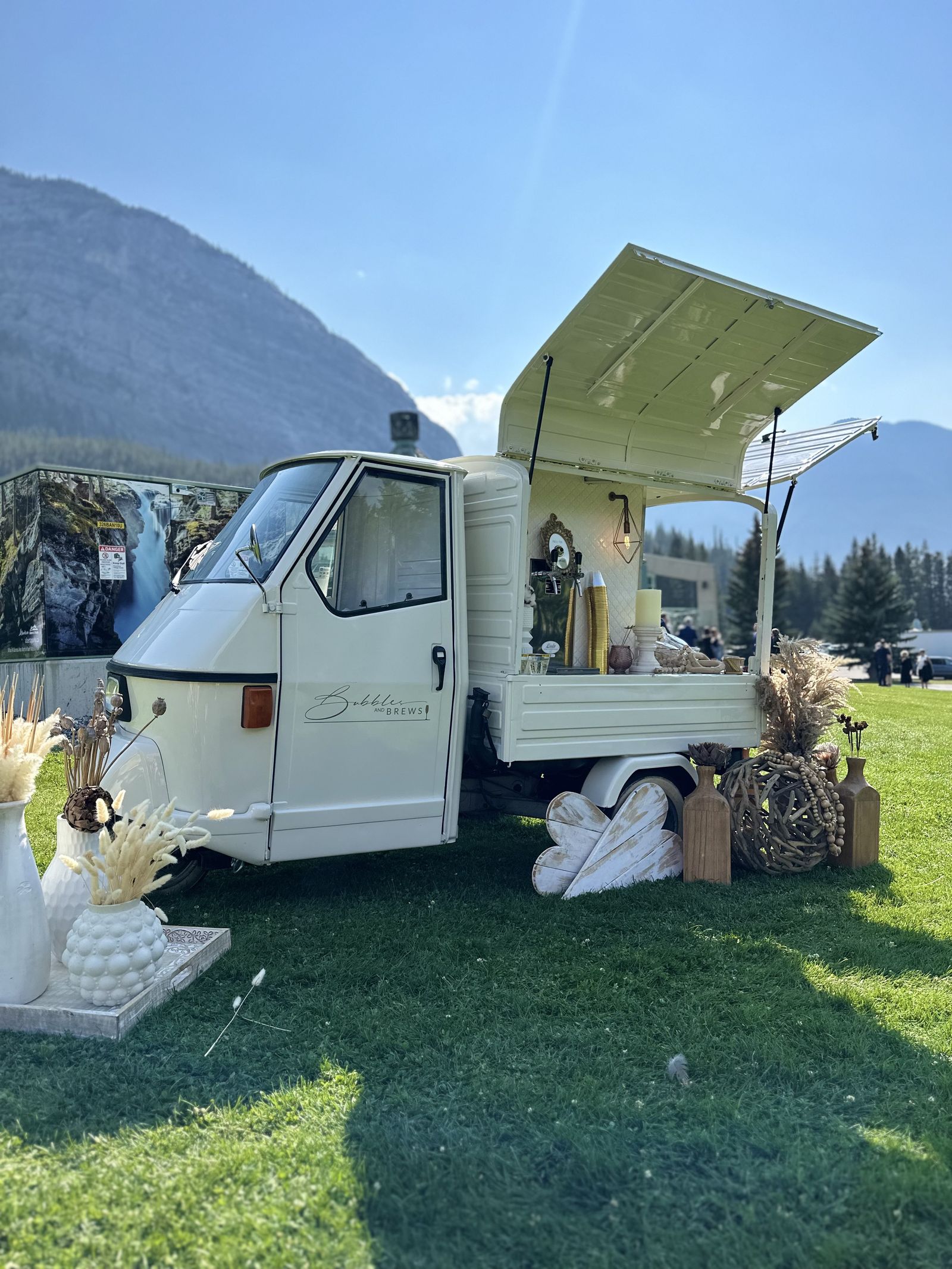 Bubbles and Brews mobile bar on the lawn of a mountain resort near Banff, Alberta, with panoramic Rocky Mountain views