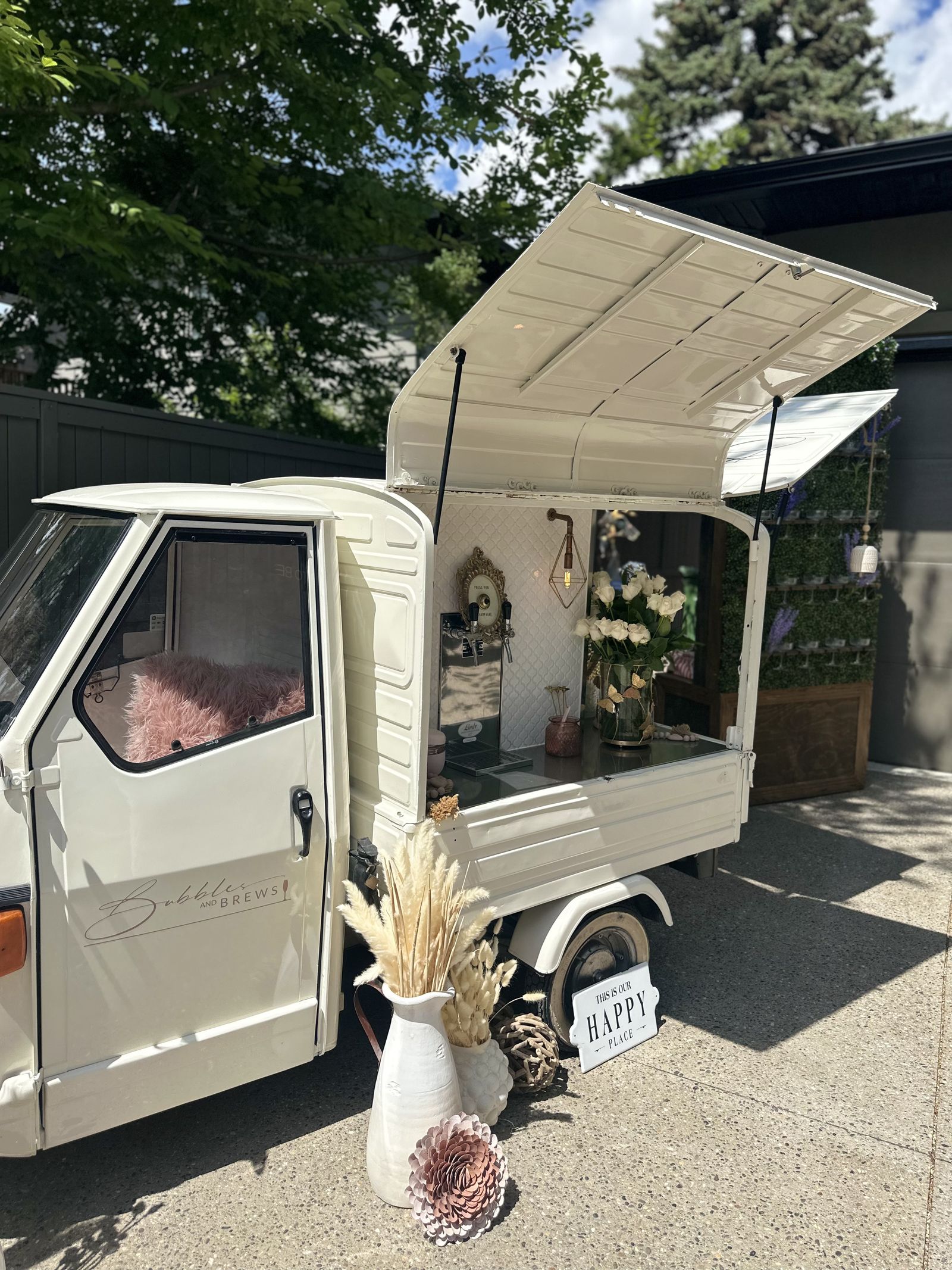 Bubbles and Brews Calgary mobile bar in clean daylight with a 'This is our Happy Place' sign and pampas grass styling
