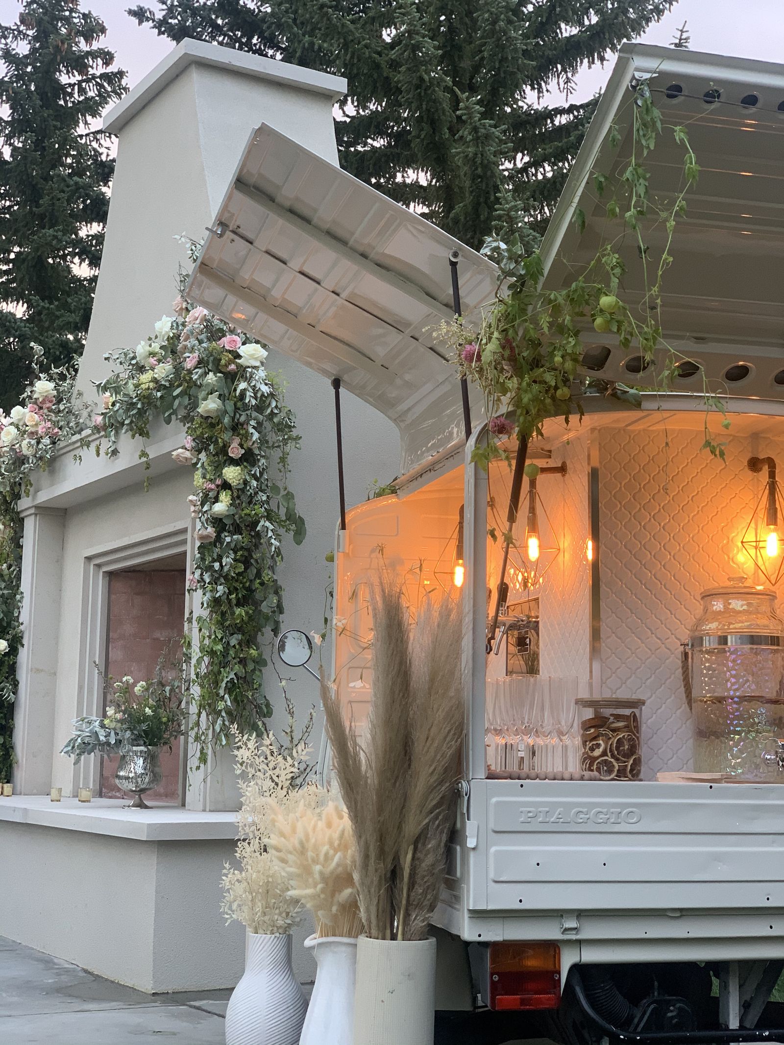 Calgary prosecco bar glowing at dusk with a full floral garland and fireplace venue backdrop