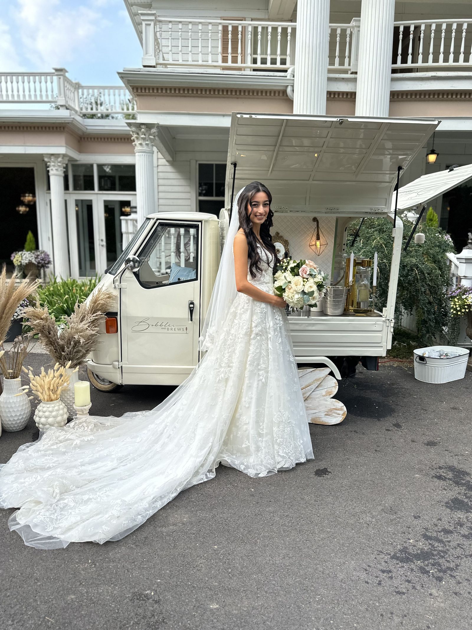 Bride in a cathedral veil and lace gown beside the mobile bar at a historic mansion venue