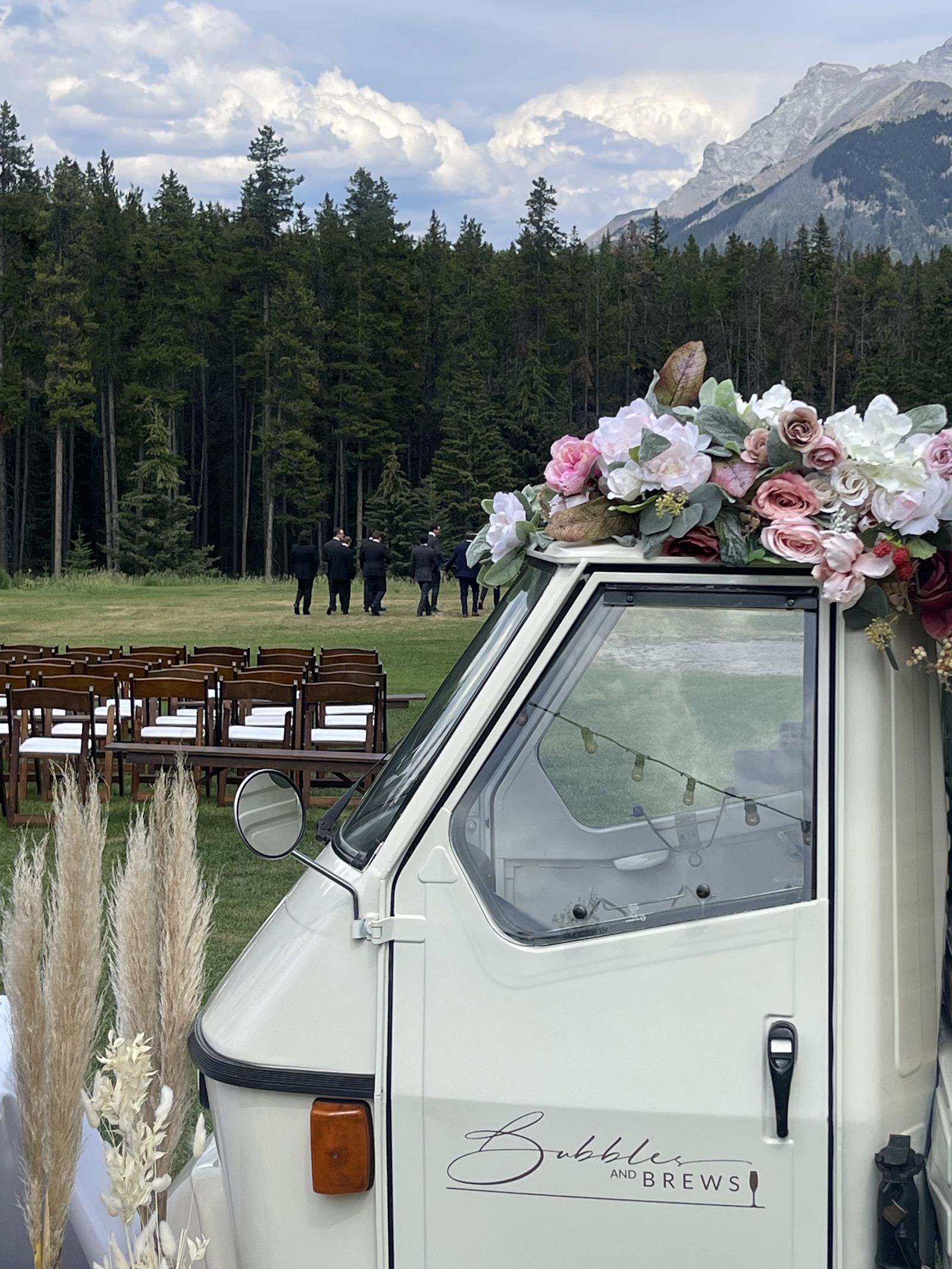 Bubbles and Brews Piaggio Ape mobile bar at a mountain wedding ceremony in Banff with the Rockies in the background