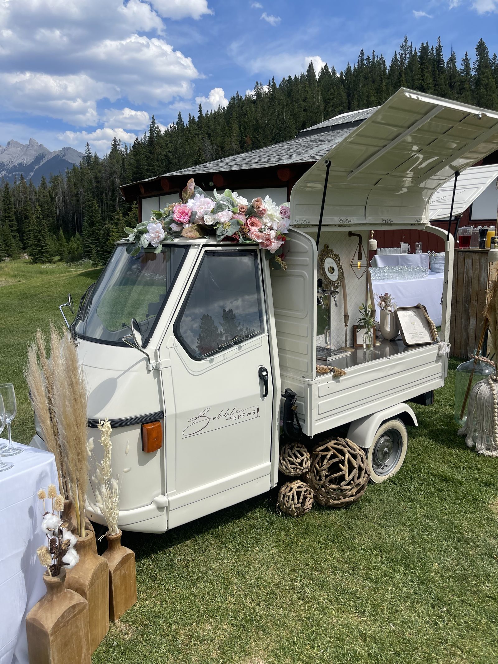 Full Bubbles and Brews mobile bar setup with florals and catering table at a mountain venue near Banff