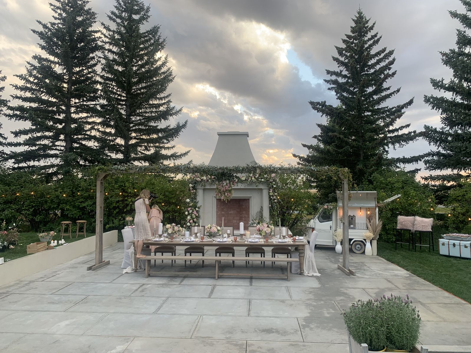 Calgary backyard wedding reception with a long banquet table and floral arch beside the Bubbles and Brews prosecco bar