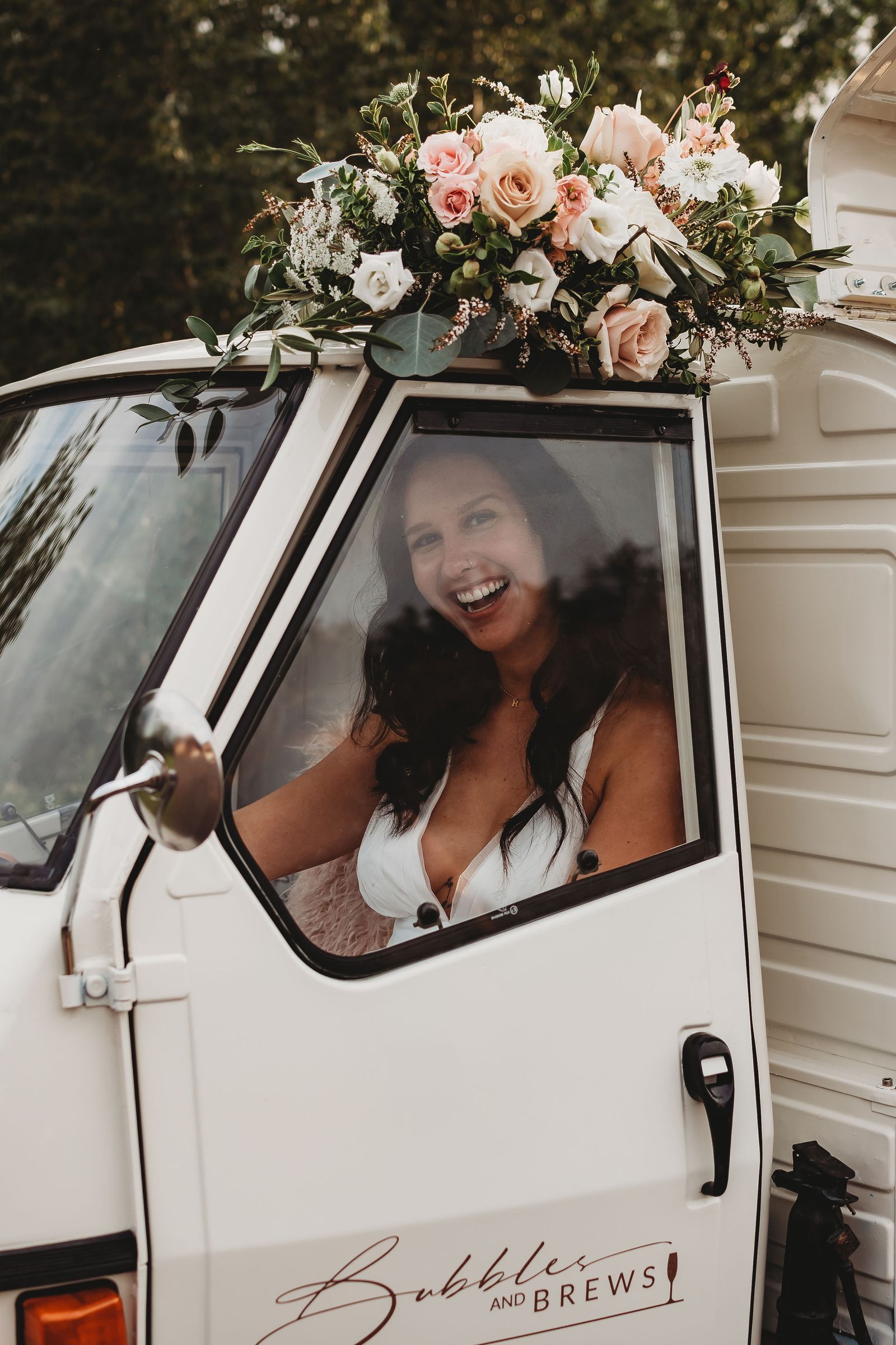 Bride photographed through the truck window with a wedding bouquet displayed on the roof