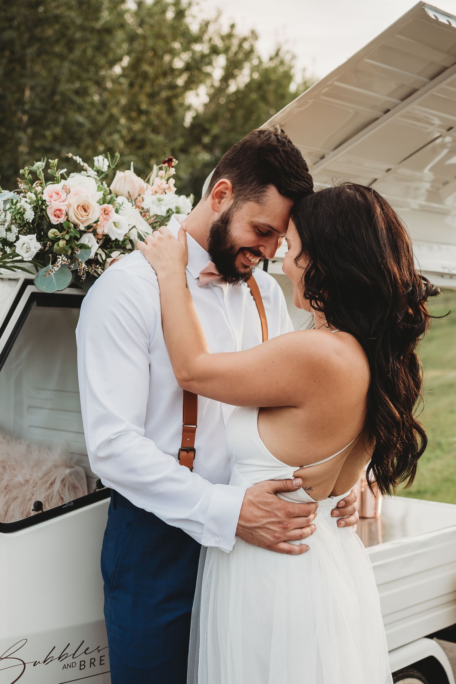 Wedding couple in a full embrace beside the mobile bar with bouquet detail, professional wedding photography