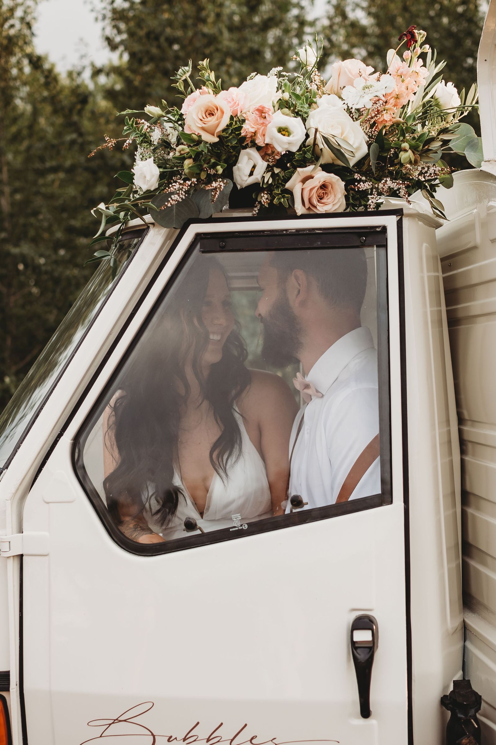 Wedding couple photographed together through the prosecco truck's cab window